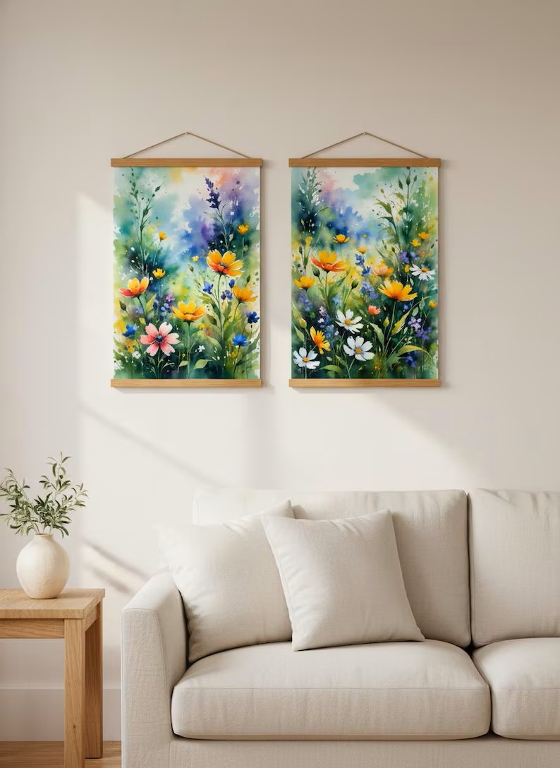 Pair of Wildflower Meadow watercolor posters on wooden hangers above a beige sofa in a sunlit living room